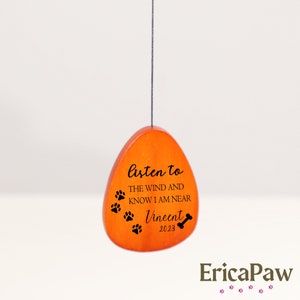 May include: Orange wooden teardrop-shaped ornament with the text "Listen to the wind and know I am near Vincent 2023" and paw prints.