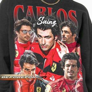 Op de afbeelding: Zwart sweatshirt met een collage van afbeeldingen van Carlos Sainz in een rood racepak. Het woord "CARLOS" is rood gedrukt en "Sainz" is wit. De tekst "BEFOREFORGET" is wit gedrukt.