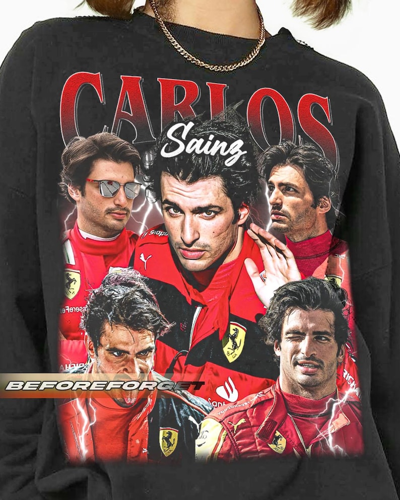 Op de afbeelding: Zwart sweatshirt met een collage van afbeeldingen van Carlos Sainz in een rood racepak. Het woord "CARLOS" is rood gedrukt en "Sainz" is wit. De tekst "BEFOREFORGET" is wit gedrukt.