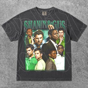 Op de afbeelding: Donkergrijs t-shirt met een collage van afbeeldingen en de groene tekst "SHAWN & GUS". De afbeeldingen tonen verschillende mannen in verschillende outfits. Het t-shirt heeft een vintage, versleten uitstraling.