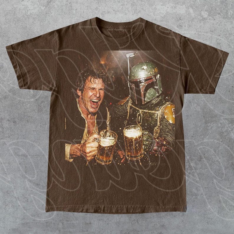 May include: A brown short-sleeve t-shirt featuring a graphic print of a laughing man and a Boba Fett character both holding glass beer mugs. The design shows the man with an open mouth and the character wearing a green and yellow helmet.