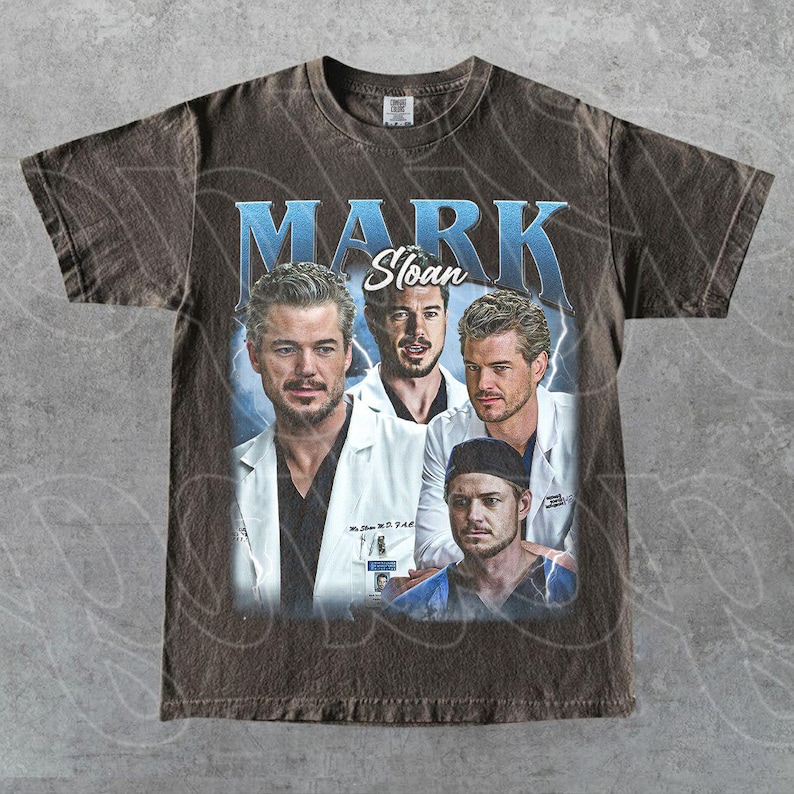 May include: Brown t-shirt with a vintage graphic of Mark Sloan from Grey's Anatomy. The design shows multiple images of the character with the name "MARK Sloan" in a blue, stylised font. The shirt has a worn, distressed appearance.