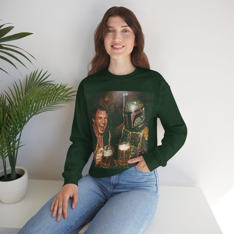 May include: A dark green long-sleeve crewneck sweatshirt featuring a graphic print of a human character and a helmeted figure in armor clinking glass beer mugs together. The sweatshirt has a ribbed neckline, cuffs, and a straight hemline.