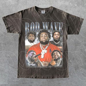 May include: A brown t-shirt featuring a graphic of Rod Wave with the text "ROD WAVE" in silver. The graphic includes multiple images of the artist in various poses, wearing jewelry and a red shirt.