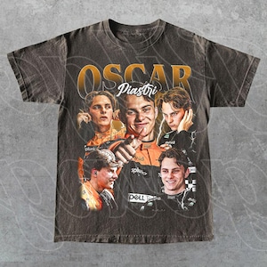 Puede incluir: Camiseta gris oscuro con un diseño gráfico de estilo vintage de Oscar Piastri. El diseño incluye múltiples imágenes de Piastri, con el nombre "OSCAR Piastri" en letras doradas. La camiseta tiene cuello redondo y mangas cortas.