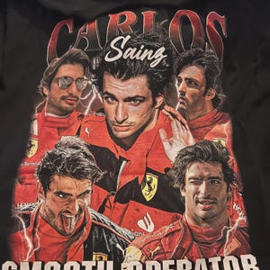 Op de afbeelding: Zwart T-shirt met een collage van afbeeldingen van Carlos Sainz in een rood racepak. De tekst "CARLOS Sainz" staat boven de afbeeldingen en "SMOOTH OPERATOR" staat onderaan. Er zijn ook bliksemflitsen.