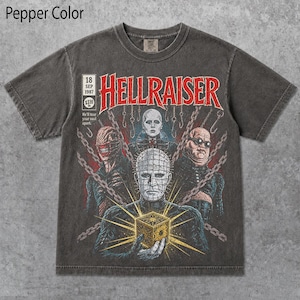 以下が含まれることがあります： 映画『ヘルレイザー』のグラフィックプリントが施されたチャコールグレーのTシャツ。赤い文字で「HELLRAISER」、日付「18 SEP 1987」、フレーズ「He'll tear your soul apart」がデザインされています。キャラクターとパズルボックスが鎖で囲まれています。