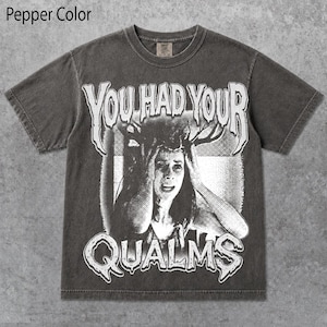 May include: A pepper-colored short-sleeve t-shirt featuring a distressed black and white graphic print of a person holding their head with antlers emerging from it. The text "YOU HAD YOUR QUALMS" is printed in a stylized font above and below the image.