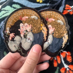 May include: Two stickers with a romantic illustration of two figures kissing, with long hair and period clothing. The stickers have a dark background with gold accents and text that reads "To The Love I Left The Pages Of The Bible In The Drawer" and "My Consciene Pressed Between The Bible In The Drawer."
