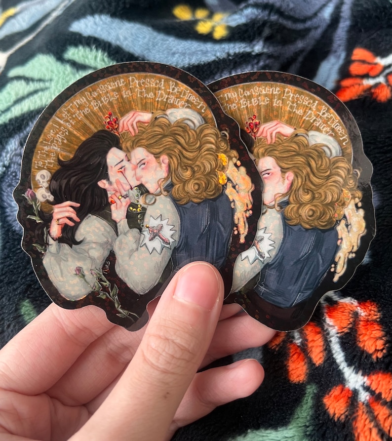 May include: Two stickers with a romantic illustration of two figures kissing, with long hair and period clothing. The stickers have a dark background with gold accents and text that reads "To The Love I Left The Pages Of The Bible In The Drawer" and "My Consciene Pressed Between The Bible In The Drawer."