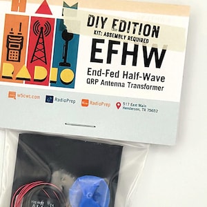 May include: A DIY kit for building an End-Fed Half-Wave QRP Antenna Transformer. The kit includes a blue and white antenna tuner, a spool of red wire, and a black circuit board with two gold-colored connectors. The kit is packaged in a clear plastic bag with a printed label that includes the name "EFHW" and the website "w5cwt.com".