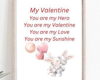 May include: A framed print with the text "My Valentine" in red, along with other loving phrases. Two cartoon bunnies are embracing, holding heart-shaped and round balloons. The print has a light wooden frame.
