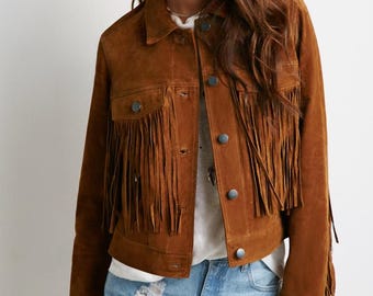 May include: A brown suede jacket with fringe detailing. The jacket has a button-up front and long sleeves.