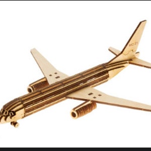 Puede incluir: Un modelo de avión de madera con el texto "MC-21" en la cola. El modelo está hecho de madera en capas y tiene un diseño realista.
