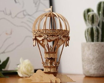 May include: A wooden model of a hot air balloon with a cloud base. The balloon has a detailed design with a basket and a flag on top.
