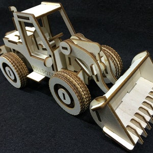 Może przedstawiać: Drewniany model buldożera z dużą łyżką. Model wykonany jest z jasnobrązowego drewna i ma szczegółowy projekt. Buldożer ma napis "BULLDOZER" nadrukowany na boku.