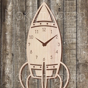 Op de afbeelding: Een houten raketvormige klok met een bruin gezicht en zwarte wijzers. De wijzerplaat van de klok heeft de cijfers 1 tot en met 12 en de woorden "10", "9", "8", "7", "6", "5", "4", "3", "2" en "11".