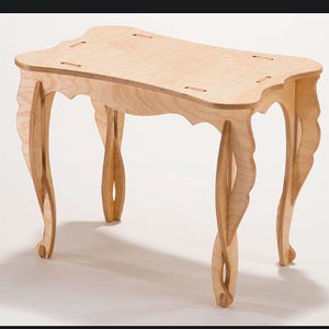 May include: A light wood table with a rectangular top and ornate legs. The table is made of plywood and has a natural wood finish.