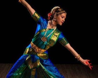 princess polly baby blue dress European female dancer performing traditional Indian dance in a vibrant blue  and gold costume on a dark stage Stock Photo