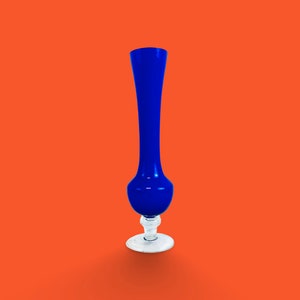 May include: A tall, blue glass vase with a flared base and a slender neck. The vase is standing on a white background.
