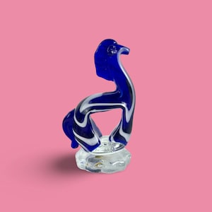 May include: A blue glass figurine of a stylized horse with white swirls. The horse is standing on a clear glass base.