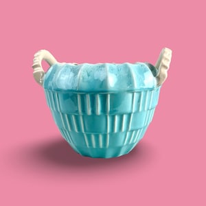 May include: A teal blue ceramic planter with two white handles. The planter has a ribbed design and is perfect for adding a touch of color to your home.