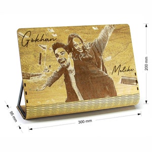 Puede incluir: Un marco de fotos de madera con una inscripción personalizada de "Gokhan" y "Melike" y una foto de una pareja. El marco mide 300 mm de ancho y 200 mm de alto.