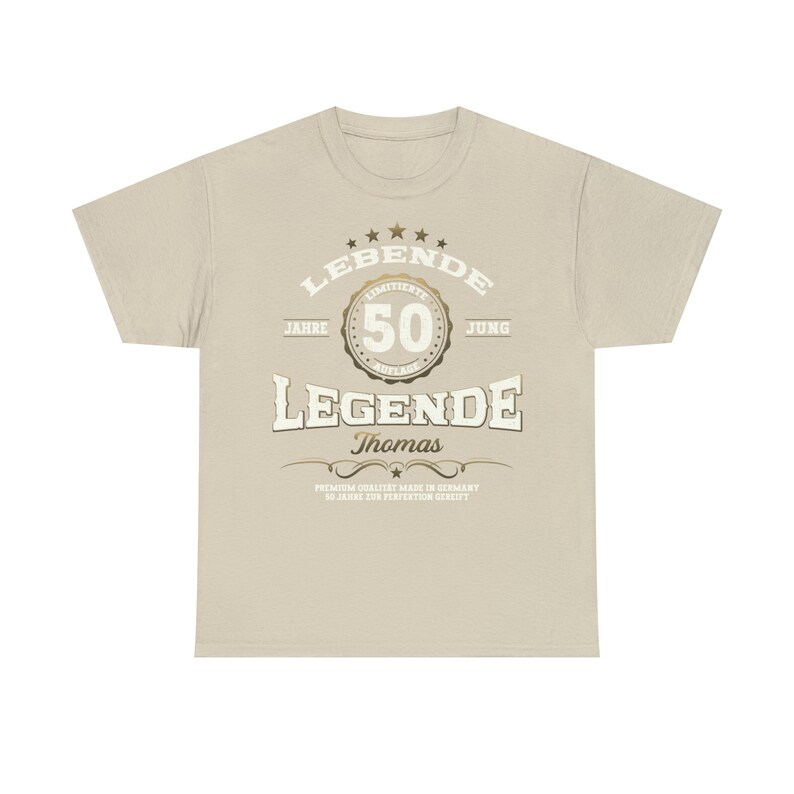 May include: A beige t-shirt with a gold graphic that says "LEBENDE 50 JAHRE JUNG LEGENDE Thomas PREMIUM QUALITAT MADE IN GERMANY 50 JAHRE ZUR PERFENTION GERIEFT"