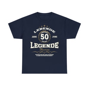 May include: Navy blue t-shirt with a gold graphic design that says "LEBENDE" with a star design above the word. The graphic also includes the text "JAHRE", "LIMITIERTE", "50", "AUFLAGE", "JUNG", "LEGENDE", "Thomas", "PREMIUM QUALITAT MADE IN GERMANY", and "50 JAHRE ZUR PERFEKTION GEREIFT".