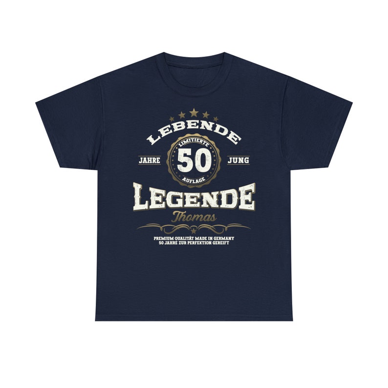 May include: Navy blue t-shirt with a gold graphic design that says "LEBENDE" with a star design above the word. The graphic also includes the text "JAHRE", "LIMITIERTE", "50", "AUFLAGE", "JUNG", "LEGENDE", "Thomas", "PREMIUM QUALITAT MADE IN GERMANY", and "50 JAHRE ZUR PERFEKTION GEREIFT".