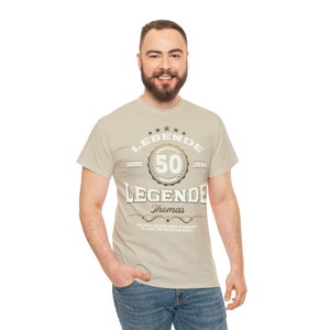 May include: A beige t-shirt with a gold graphic that says "LEBENDE 50 JAHRE JUNG LEGENDE Thomas".