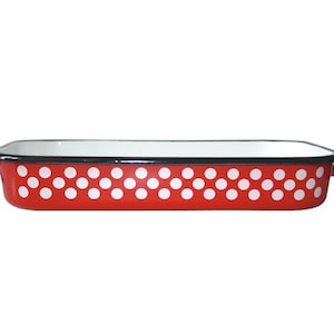 May include: Red enamel baking dish with white polka dots and black trim. The dish has two handles on the sides.