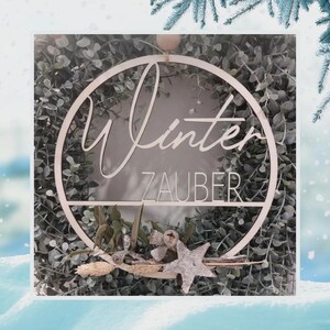Pu&ograve; includere: Una ghirlanda di legno con un cerchio di verde e un cartello che dice "Winter Zauber".