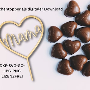 Könnte beinhalten: Ein goldener herzförmiger Kuchentopper mit dem Wort "mama" in Kursivschrift. Der Topper befindet sich auf einem weißen Hintergrund mit einem Haufen Schokoladenherzen, auf denen "Merci" steht.
