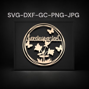 Könnte beinhalten: Ein Wandkunstwerk aus Holz mit einem kreisförmigen Design, Schmetterlingen, Blumen und dem deutschen Wort "hereinspaziert". Das Kunstwerk ist in einem schwarzen Rahmen eingefasst, der einen Kontrast zum hellen Holz bildet.