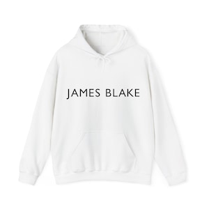 May include: White hooded sweatshirt with a black print that says "JAMES BLAKE" on the front.