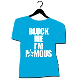 May include: A light blue t-shirt with the text "BLUCK ME I'M FAMOUS" in white, along with a white star graphic. The shirt is hanging on a black hanger against a white background.