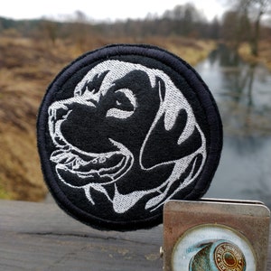 Op de afbeelding: Zwart-witte geborduurde patch van een hondenkop met een witte achtergrond en een zwarte omtrek. De patch is rond en heeft een zwarte rand.