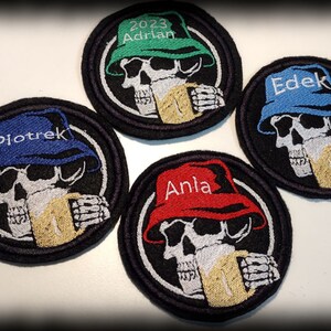 Op de afbeelding: Geborduurde patches met een schedelontwerp met een hoed en een mok. Elke patch heeft een andere naam op de hoed geborduurd: Piotr, Adrian, Edek en Ania. De patches zijn zwart met een witte rand.