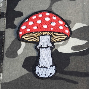Peut inclure: Écusson brodé représentant un champignon rouge à pois blancs et un dessous beige. Le champignon a un pied gris, sur un fond camouflage. Convient aux vestes, sacs ou autres articles en tissu. Hauteur approximative de 7 cm.