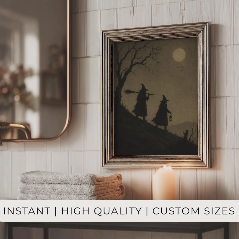 May include: A framed wall art print featuring a silhouette illustration of two figures in pointed hats walking up a hill under a full moon. One figure carries a broomstick and the other a lantern. The artwork is displayed in a metallic frame.