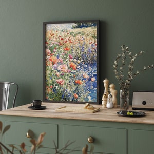 Pode incluir: Uma pintura em aquarela emoldurada que representa um campo de flores silvestres em tons de rosa, vermelho e azul. As flores est&atilde;o dispostas em um padr&atilde;o solto e natural, e o fundo &eacute; um verde suave e desfocado.