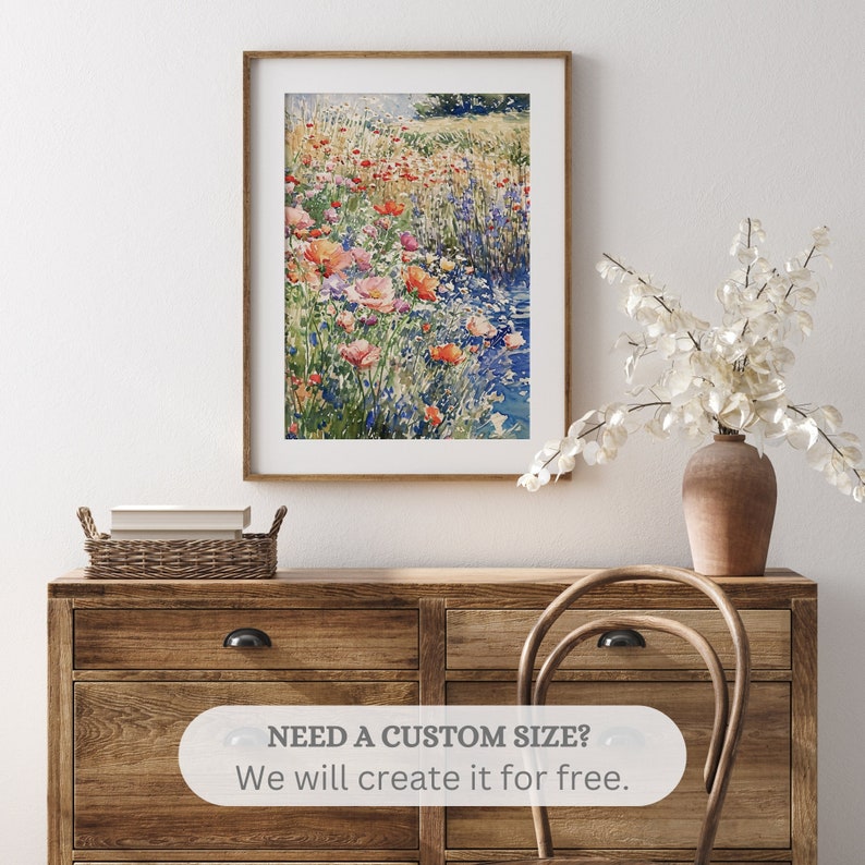 Pode incluir: Uma pintura a aquarela emoldurada de um campo de flores silvestres, incluindo papoulas rosa e vermelhas, com um riacho que atravessa o centro.