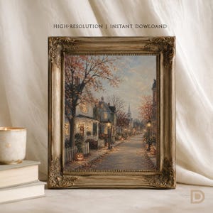 May include: A framed wall art print featuring an oil painting of a quiet street at dusk with autumn trees, glowing street lamps, and jack-o'-lanterns on the ground. The ornate, antique-style gold frame surrounds the detailed suburban scene.