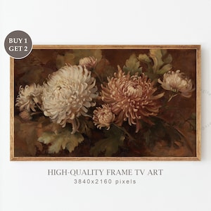 Op de afbeelding: Een ingelijste bloemenprint met witte en perzik chrysanten en groene bladeren tegen een donkerbruine achtergrond. Het kunstwerk zit in een houten lijst. Tekst op de afbeelding luidt "HIGH-QUALITY FRAME TV ART" en "BUY 1 GET 2".