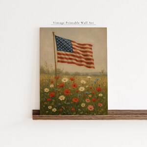 May include: Vintage printable wall art featuring an American flag waving in a field of wildflowers. The artwork showcases the flag's red and white stripes and blue star field, with a backdrop of colorful blooms.