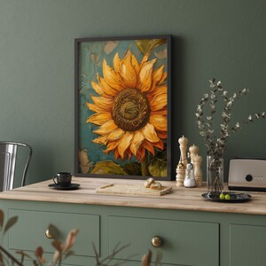 K&ouml;nnte beinhalten: Ein gerahmtes Gem&auml;lde einer Sonnenblume mit gelben Bl&uuml;tenbl&auml;ttern und einer dunkelbraunen Mitte. Das Gem&auml;lde befindet sich auf einem strukturierten Hintergrund mit einem blauen und gr&uuml;nen Farbschema. Der Rahmen ist schwarz und das Gem&auml;lde h&auml;ngt an einer gr&uuml;nen Wand.