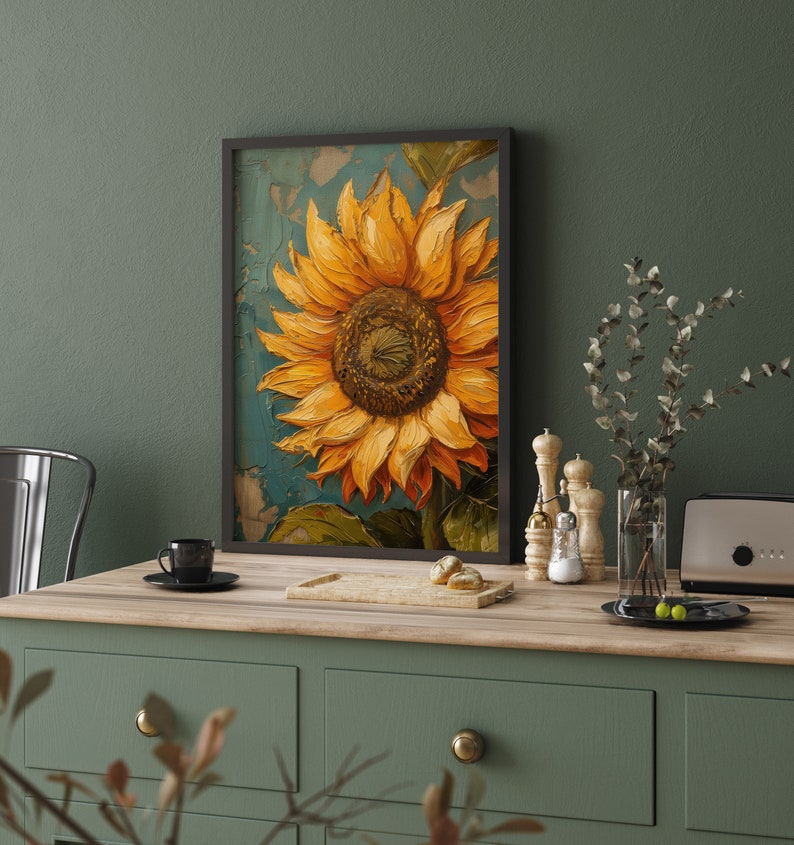 K&ouml;nnte beinhalten: Ein gerahmtes Gem&auml;lde einer Sonnenblume mit gelben Bl&uuml;tenbl&auml;ttern und einer dunkelbraunen Mitte. Das Gem&auml;lde befindet sich auf einem strukturierten Hintergrund mit einem blauen und gr&uuml;nen Farbschema. Der Rahmen ist schwarz und das Gem&auml;lde h&auml;ngt an einer gr&uuml;nen Wand.
