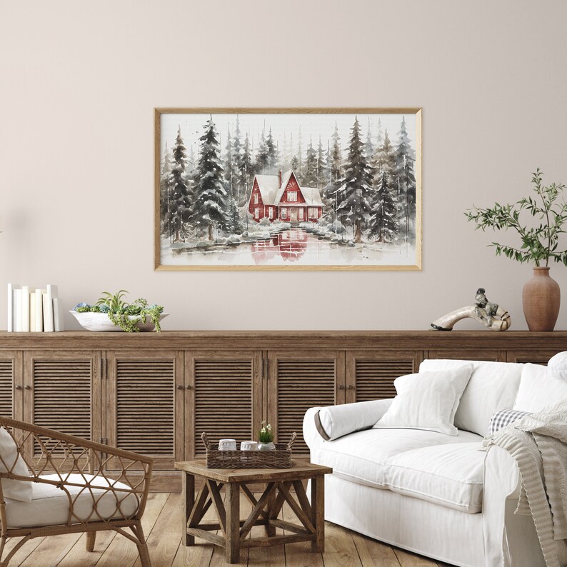 May include: A watercolor painting of a red cabin in a snowy forest. The cabin has two stories and a white roof. The trees are tall and slender, and the snow is falling softly. The painting is framed in a simple wooden frame.