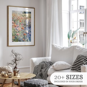 Pode incluir: Uma pintura a aquarela emoldurada de um campo de flores rosa e vermelhas com um riacho azul que o atravessa. A pintura est&aacute; pendurada em uma parede branca em uma sala de estar.